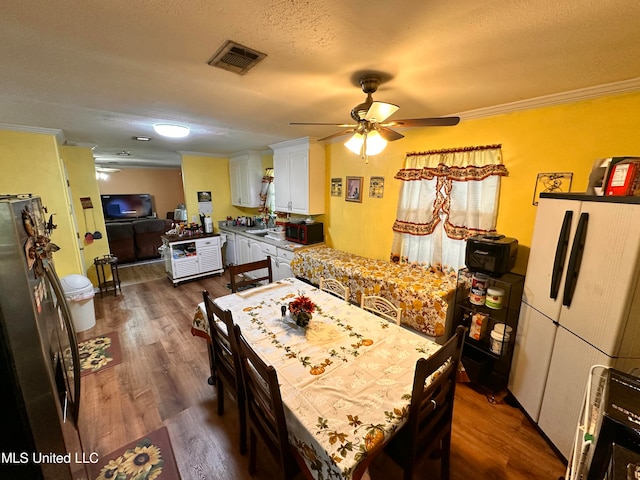 dining space featuring dark hardwood / wood-style floors, ceiling fan, ornamental molding, and a textured ceiling