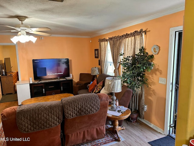 living room featuring ceiling fan, light hardwood / wood-style flooring, a textured ceiling, and ornamental molding