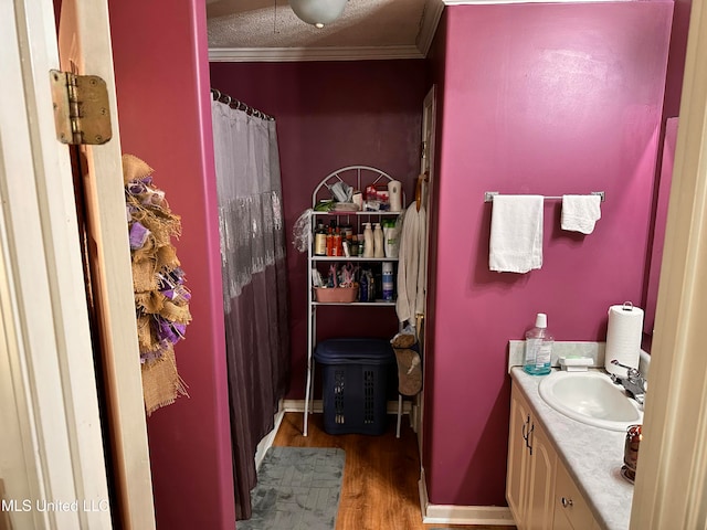 bathroom with hardwood / wood-style floors, vanity, ornamental molding, and a textured ceiling