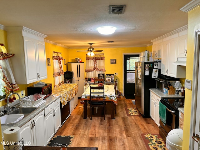 kitchen featuring hardwood / wood-style floors, black electric range oven, white cabinets, crown molding, and sink