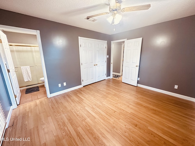 1154 E Old Pass Rd, Long Beach, MS 39560 - unfurnished bedroom with light wood finished floors, baseboards, a closet, a textured ceiling, and ensuite bathroom