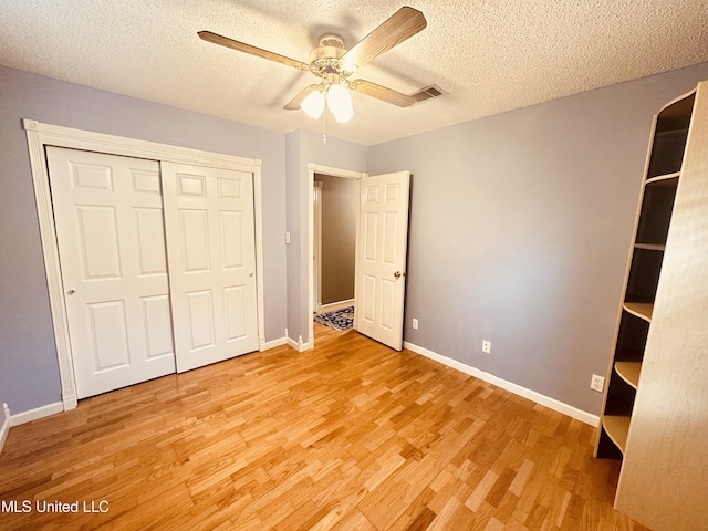 1154 E Old Pass Rd, Long Beach, MS 39560 - unfurnished bedroom featuring light wood finished floors, baseboards, a textured ceiling, a closet, and a ceiling fan