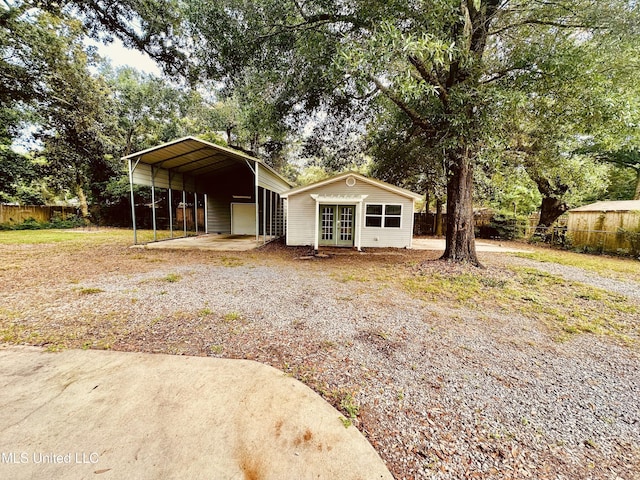 1154 E Old Pass Rd, Long Beach, MS 39560 - view of front of house featuring french doors, a carport, an outbuilding, and view of scattered trees