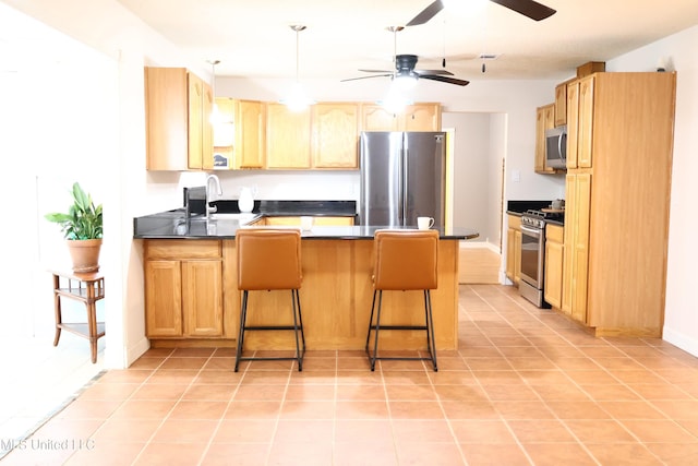 1154 E Old Pass Rd, Long Beach, MS 39560 - kitchen with appliances with stainless steel finishes, a peninsula, dark countertops, a ceiling fan, and a breakfast bar area