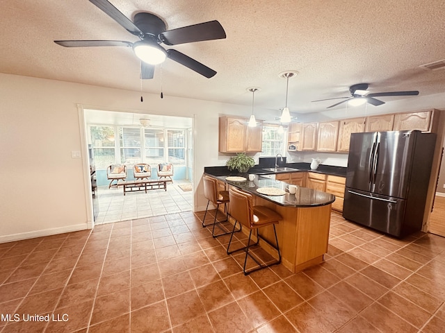 1154 E Old Pass Rd, Long Beach, MS 39560 - kitchen featuring freestanding refrigerator, light brown cabinets, dark countertops, a ceiling fan, and a textured ceiling