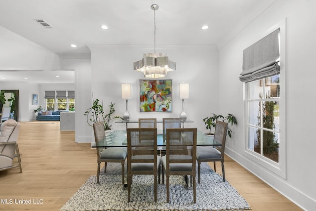 dining area featuring light wood-type flooring, an inviting chandelier, and ornamental molding