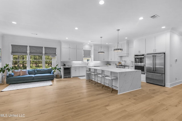 kitchen with appliances with stainless steel finishes, a center island, white cabinetry, and beverage cooler