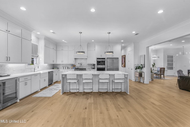 kitchen with wine cooler, white cabinetry, a kitchen island, and stainless steel appliances