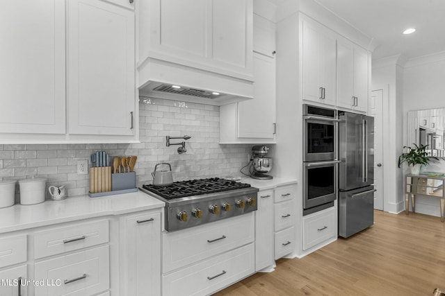 kitchen featuring decorative backsplash, stainless steel appliances, crown molding, light hardwood / wood-style floors, and white cabinetry