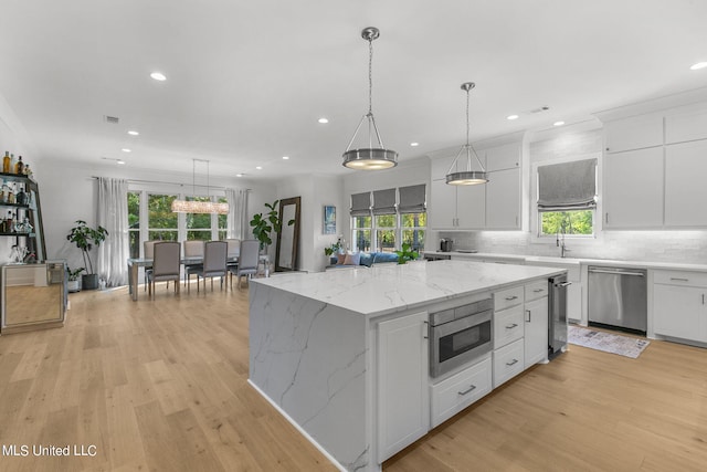 kitchen featuring pendant lighting, light hardwood / wood-style floors, a kitchen island, white cabinetry, and stainless steel appliances