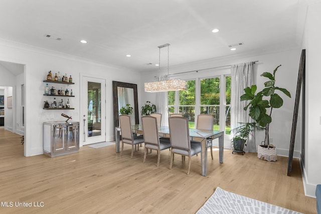 dining space featuring crown molding and light hardwood / wood-style flooring