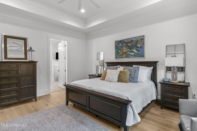 bedroom with ensuite bathroom, ornamental molding, a tray ceiling, ceiling fan, and light hardwood / wood-style floors