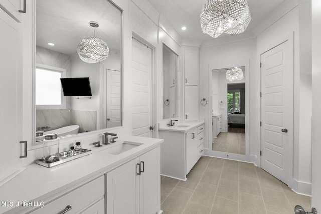 bathroom featuring a bath, vanity, and a chandelier