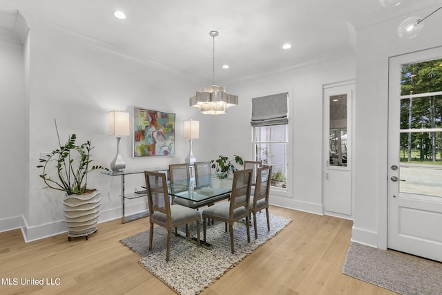 dining room with crown molding, a notable chandelier, and light wood-type flooring