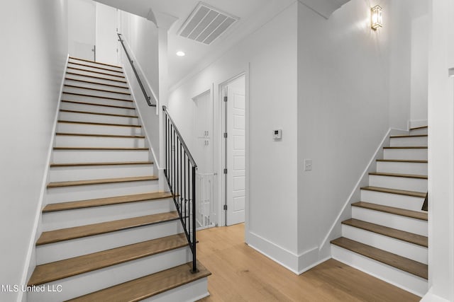 staircase featuring wood-type flooring and ornamental molding