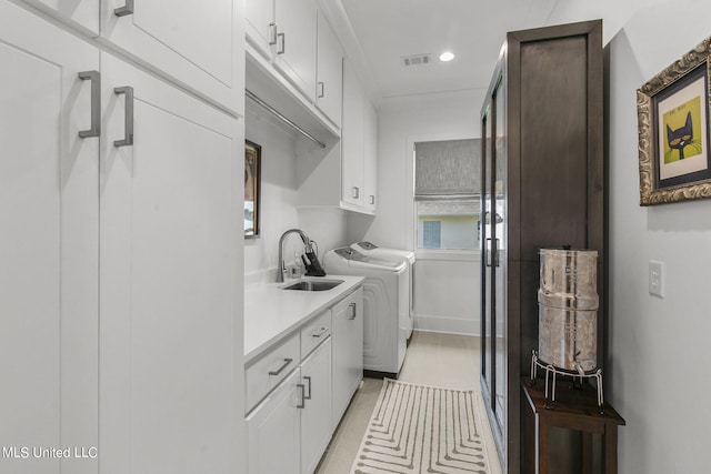 washroom featuring washing machine and clothes dryer, sink, and cabinets