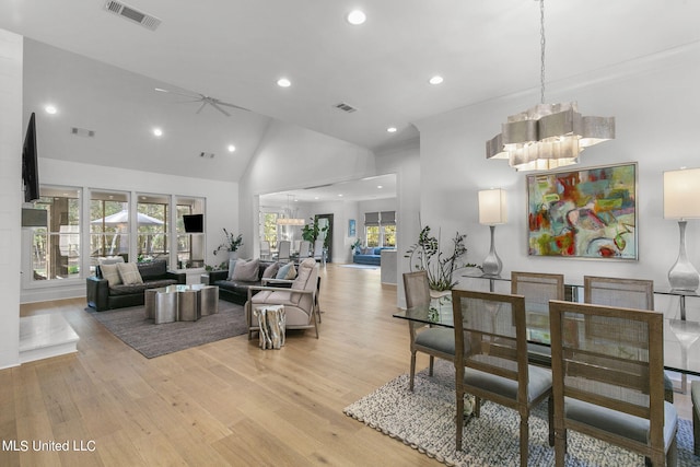 living room featuring ceiling fan with notable chandelier, light hardwood / wood-style floors, and high vaulted ceiling