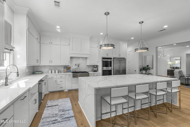 kitchen featuring white cabinetry, a center island, light stone countertops, a breakfast bar area, and appliances with stainless steel finishes