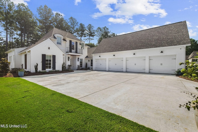 view of front of home featuring a balcony, a garage, and a front lawn