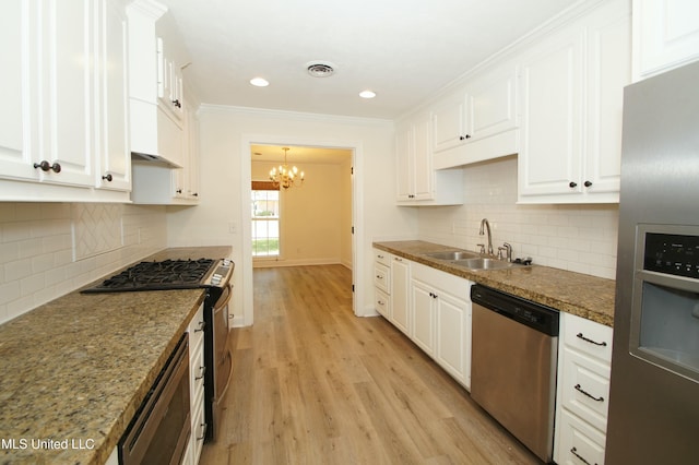 kitchen with light hardwood / wood-style floors, an inviting chandelier, white cabinetry, appliances with stainless steel finishes, and sink