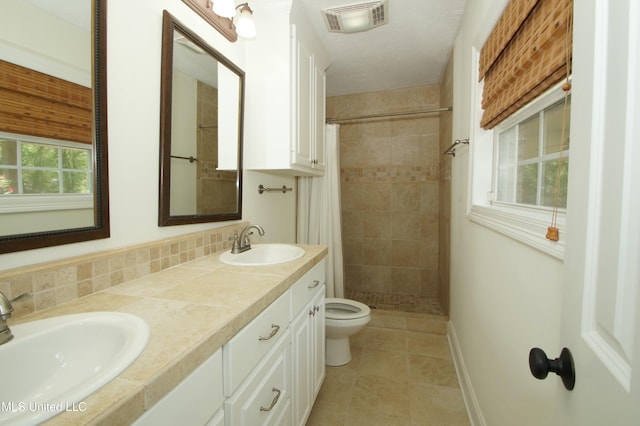 bathroom with toilet, tile patterned flooring, curtained shower, and vanity