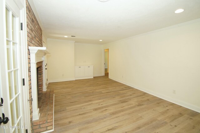 unfurnished living room featuring a fireplace, ornamental molding, and light hardwood / wood-style flooring