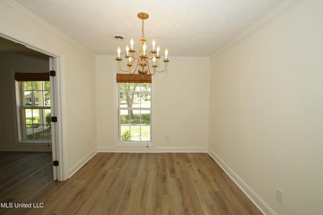 unfurnished dining area with ornamental molding, an inviting chandelier, and hardwood / wood-style flooring