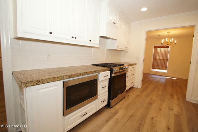 kitchen featuring stainless steel range with gas cooktop, decorative light fixtures, light hardwood / wood-style floors, built in microwave, and white cabinets