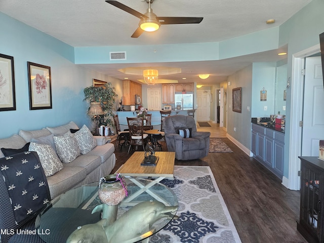 living room featuring a textured ceiling, ceiling fan, and dark hardwood / wood-style floors