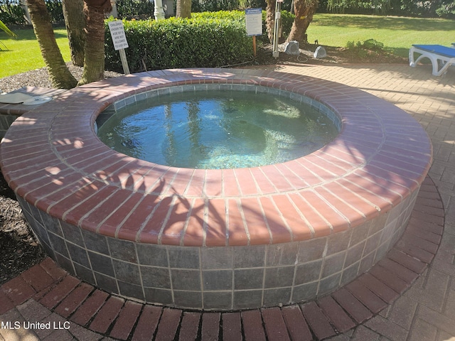 view of pool with a lawn and an in ground hot tub