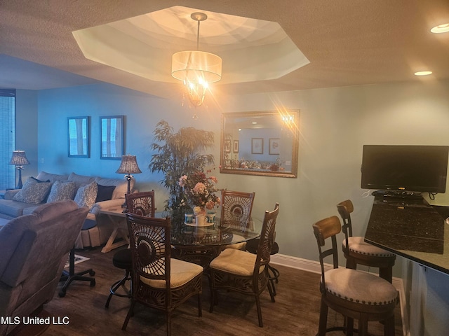 dining area with dark hardwood / wood-style flooring, a textured ceiling, and a tray ceiling