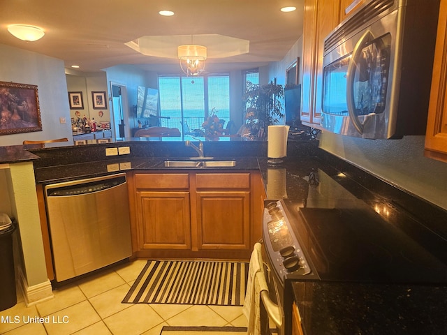 kitchen featuring sink, appliances with stainless steel finishes, a tray ceiling, light tile patterned flooring, and a chandelier