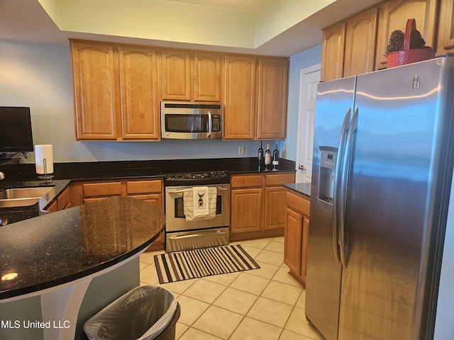 2668 Beach Blvd Unit 702, Biloxi, MS 39531 - kitchen featuring appliances with stainless steel finishes, light tile patterned flooring, a sink, dark stone countertops, and a raised ceiling