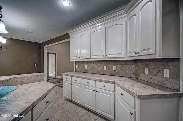127 Rockbridge Cir, Clinton, MS 39056 - kitchen with backsplash, white cabinetry, light tile patterned floors, ornamental molding, and a textured ceiling