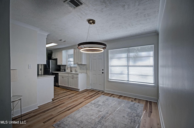 226 N Shenandoah Rd, Brandon, MS 39047 - kitchen with light countertops, a textured ceiling, white cabinetry, decorative backsplash, and wood finished floors