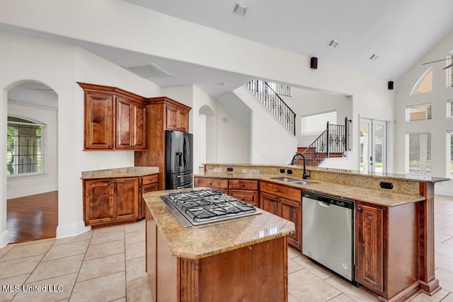 17000 River Pl, Vancleave, MS 39565 - kitchen featuring appliances with stainless steel finishes, a sink, a kitchen island, arched walkways, and light stone counters