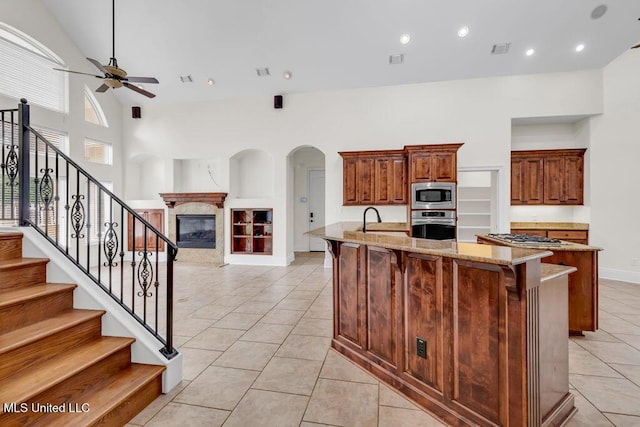 17000 River Pl, Vancleave, MS 39565 - kitchen featuring stainless steel appliances, a ceiling fan, light stone countertops, light tile patterned flooring, and a premium fireplace