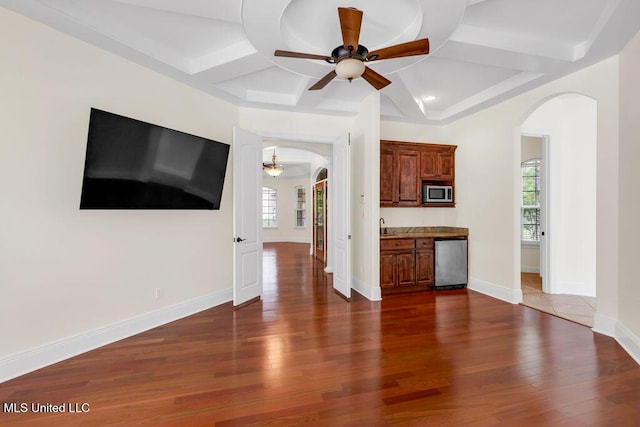 17000 River Pl, Vancleave, MS 39565 - unfurnished living room with arched walkways, a ceiling fan, coffered ceiling, dark wood-style flooring, and recessed lighting