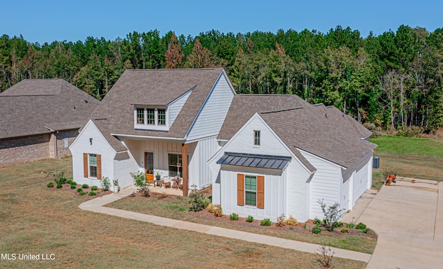 modern farmhouse featuring a front lawn, covered porch, and a garage