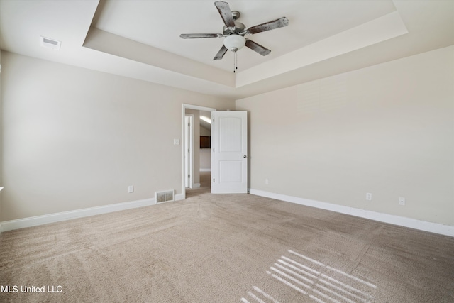 carpeted empty room featuring a tray ceiling and ceiling fan