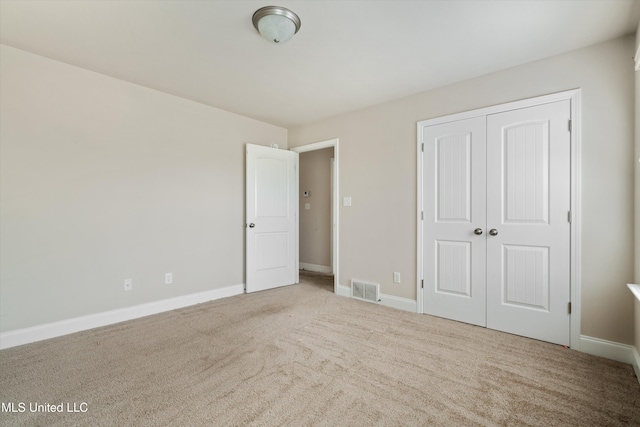 unfurnished bedroom featuring light colored carpet and a closet