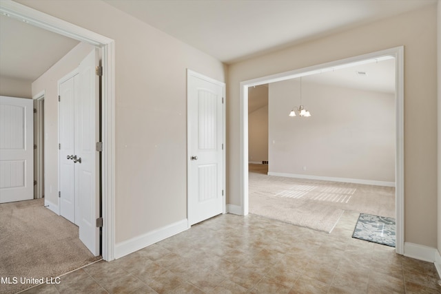 hallway with lofted ceiling, carpet floors, and a notable chandelier