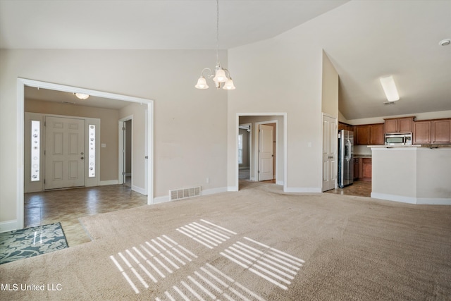 unfurnished living room with light carpet, high vaulted ceiling, and a chandelier