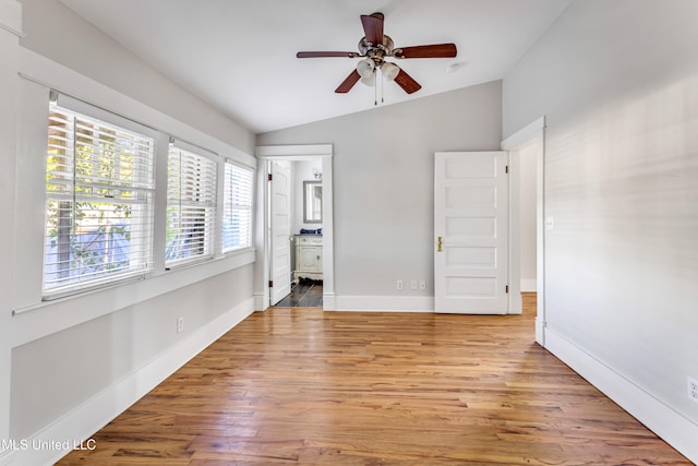 unfurnished bedroom with lofted ceiling, ensuite bathroom, light wood-type flooring, and ceiling fan