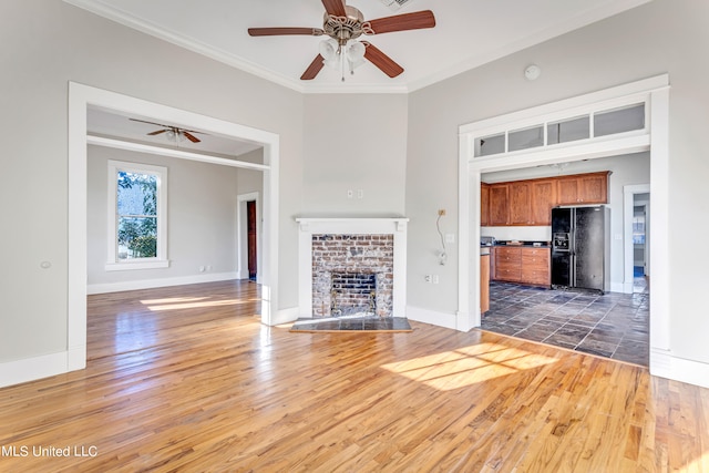 unfurnished living room featuring dark wood-type flooring, crown molding, a brick fireplace, and ceiling fan