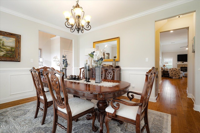 8063 Elizabeth Dr, Olive Branch, MS 38654 - dining room featuring a chandelier, ornamental molding, wood-type flooring, wainscoting, and a fireplace