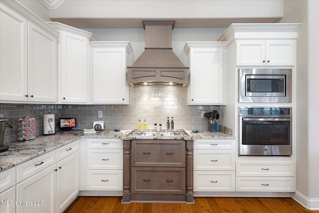 8063 Elizabeth Dr, Olive Branch, MS 38654 - kitchen with stainless steel appliances, custom range hood, white cabinets, and decorative backsplash