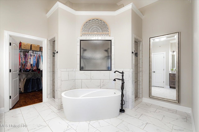 8063 Elizabeth Dr, Olive Branch, MS 38654 - bathroom featuring marble look tiles, a walk in closet, a freestanding tub, a stall shower, and a wainscoted wall