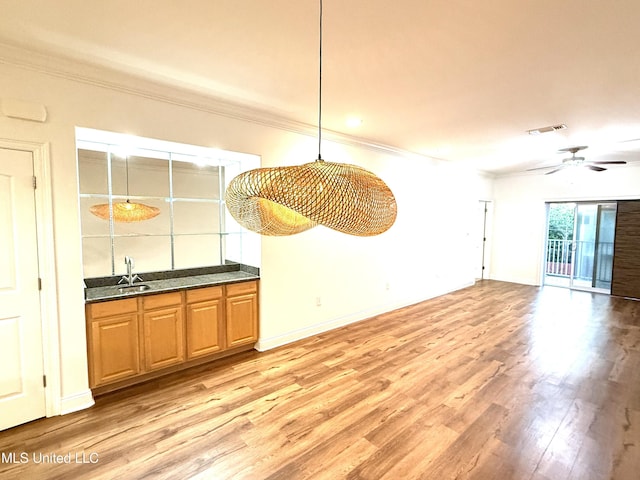 unfurnished dining area featuring light wood finished floors, visible vents, crown molding, and ceiling fan