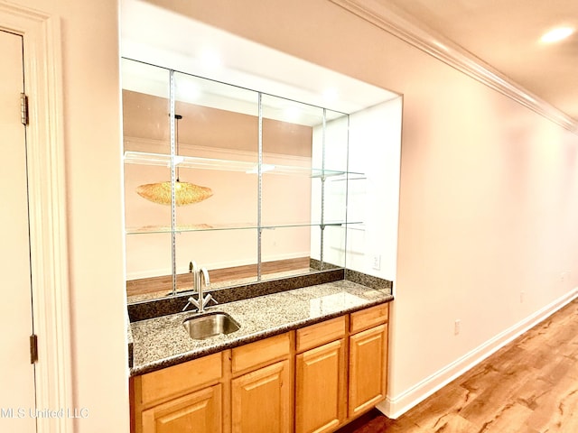 bar with ornamental molding, light wood-type flooring, baseboards, and a sink